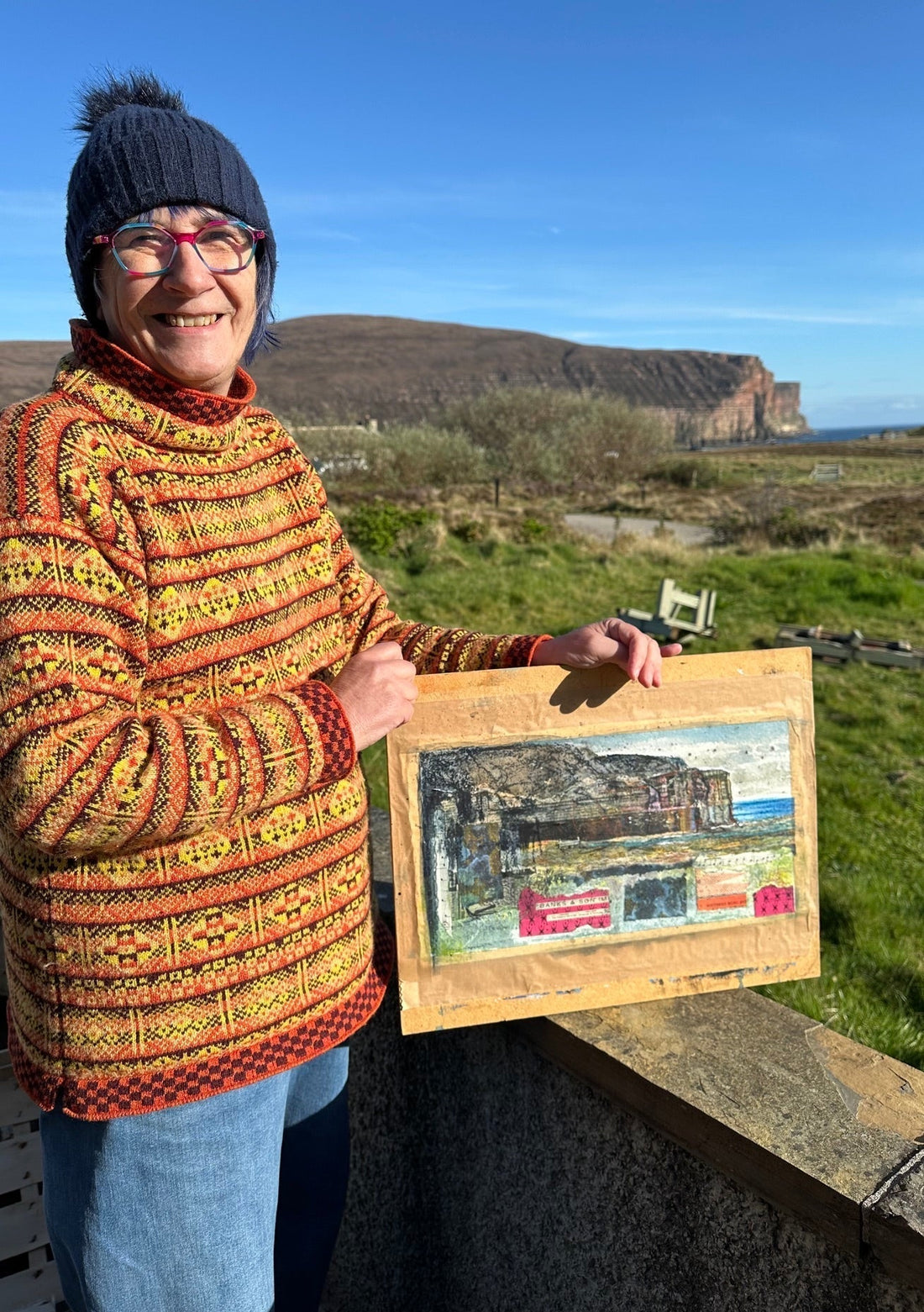 Orkney artist Jane Glue standing with her painting in Rackwick in Hoy, Orkney.