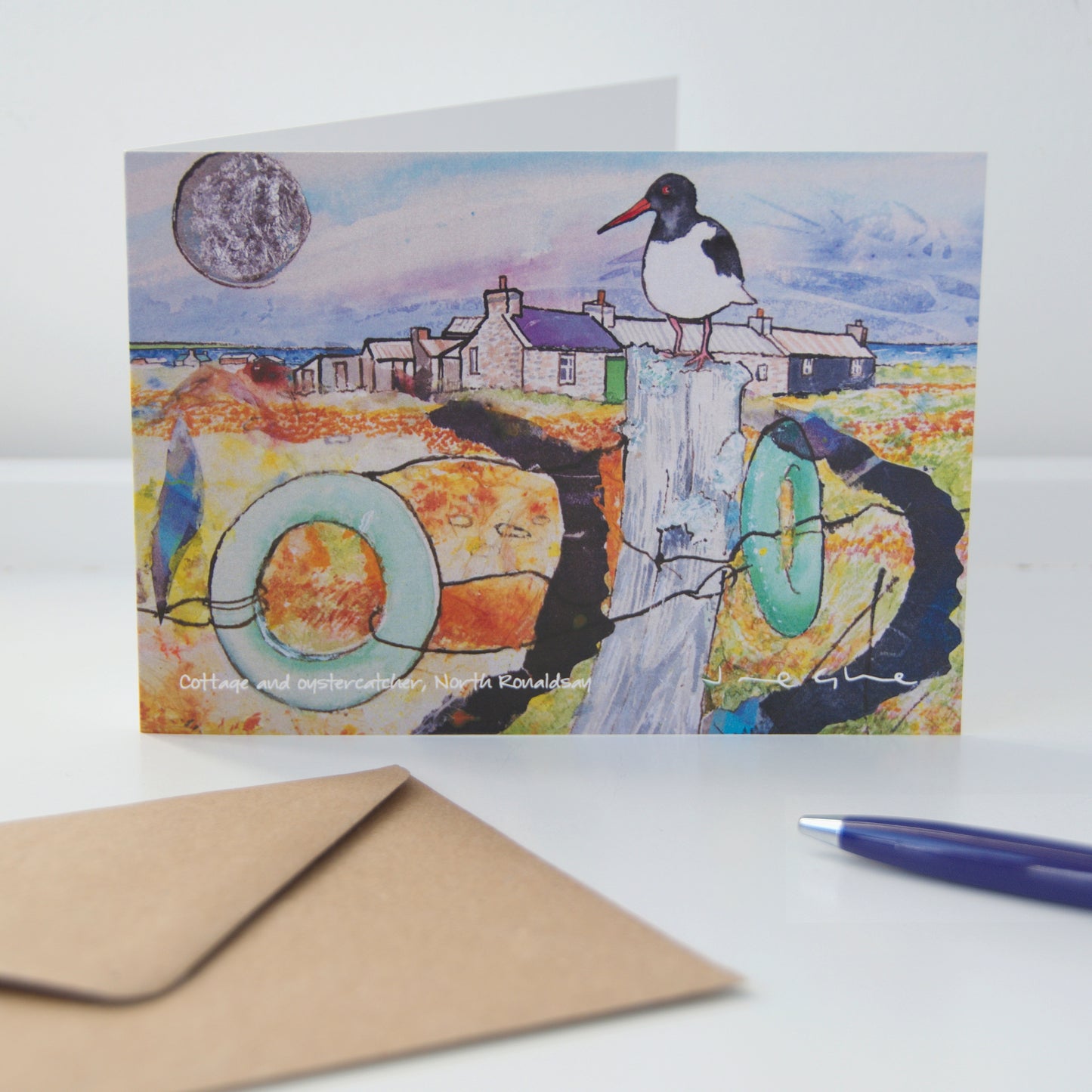 A folded card printed with a mixed media painting of an oystercatcher sitting on a fence post with a house and silver sun in North Ronaldsay by Orkney artist Jane Glue, Scotland