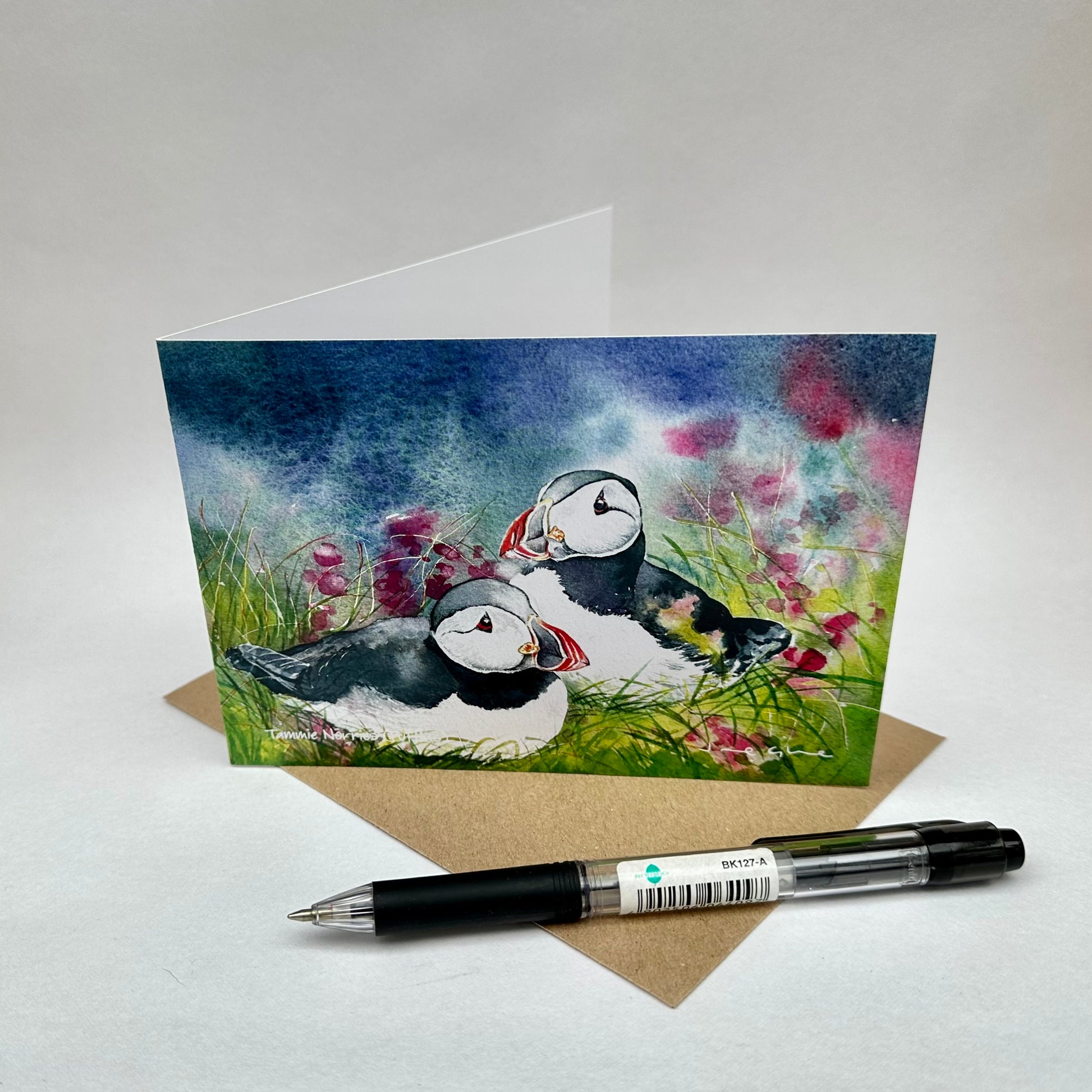Folded blank card of two puffins sitting amongst wildflowers in Westray