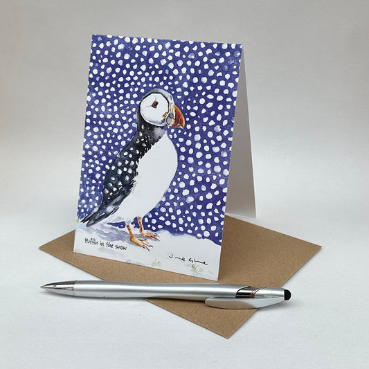 A folded blank card of a puffin standing in the snow