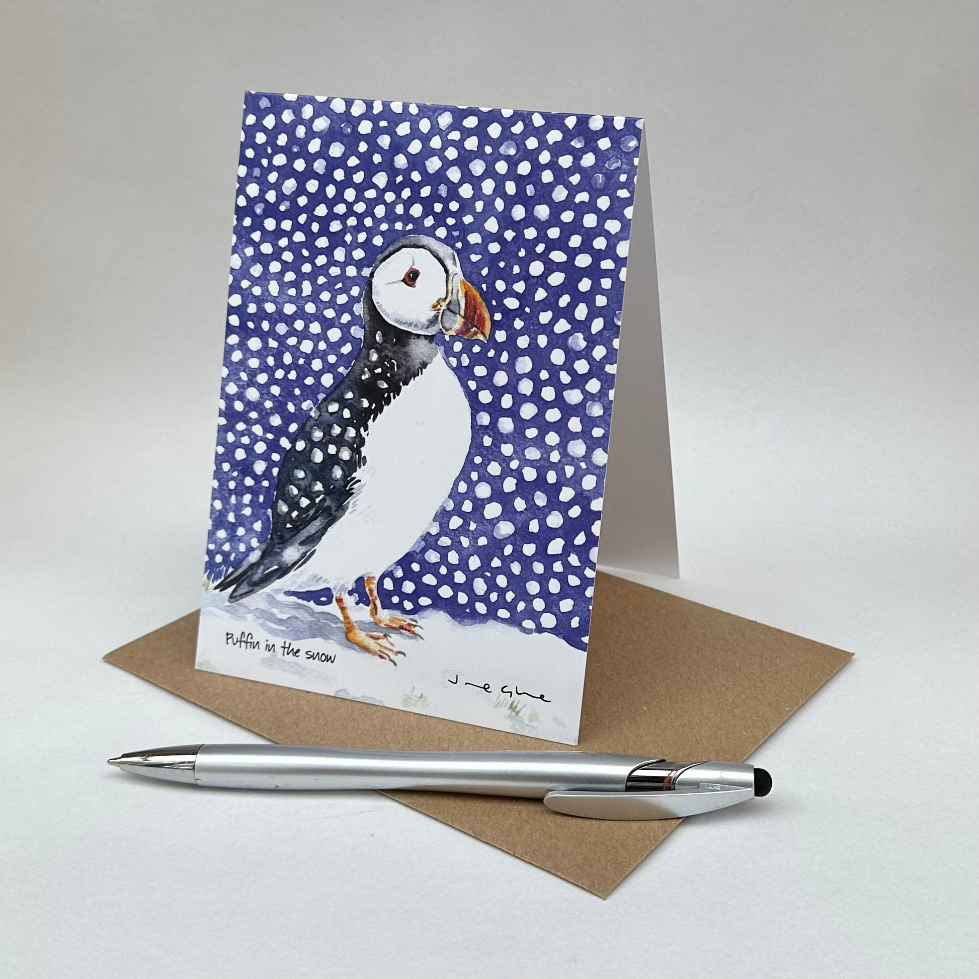 A folded blank card of a puffin standing in the snow